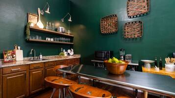 A kitchen with a central island, bar stools, a microwave, and a bowl of fruit.