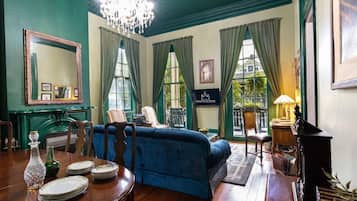 Una habitación con una cama grande, una mesa de comedor con platos y vasos, una araña y un cartel que indica el nombre de la habitación.