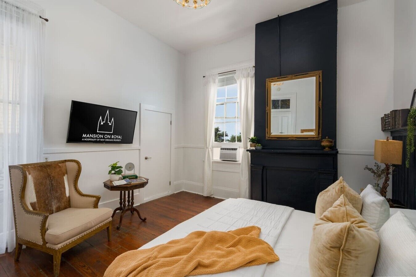 Een hotelkamer met een bed, een stoel, een televisie, een open haard en een raam.