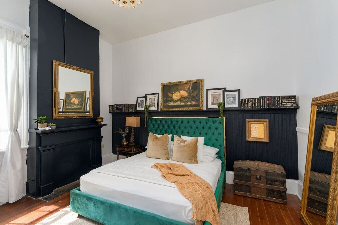 A bedroom with a bed, a dresser, a mirror, and a fireplace.