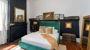 Een slaapkamer met een bed, een kast, een spiegel en een open haard.