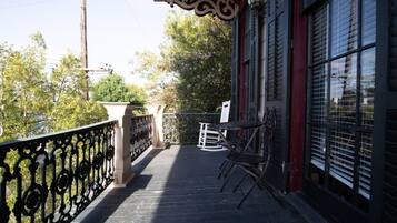 A balcony with a metal railing, a rocking chair, and a table.