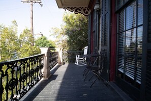 A balcony with a metal railing, a rocking chair, and a table.