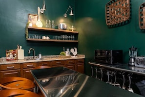 A kitchen with a stainless steel table, wooden cabinets, a microwave, and a blender.