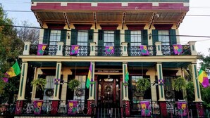 A building with a balcony, a sign reading 'Royal Street Courtyard,' and flags. - Marigny Historic 1BD Steps to Jazz & Frenchmen (New Orleans)