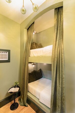 A bunk bed with a headboard, a bedside table with a lamp, and a small plant.
