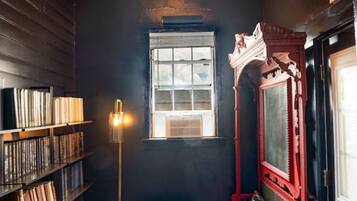 A room with a bookshelf, a red bench, a window, and a red wall.