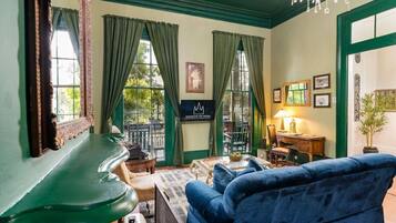A room with a green piano, a blue sofa, a chessboard, and a chandelier.
