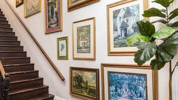 A staircase with a wooden handrail and a white wall adorned with framed artworks.