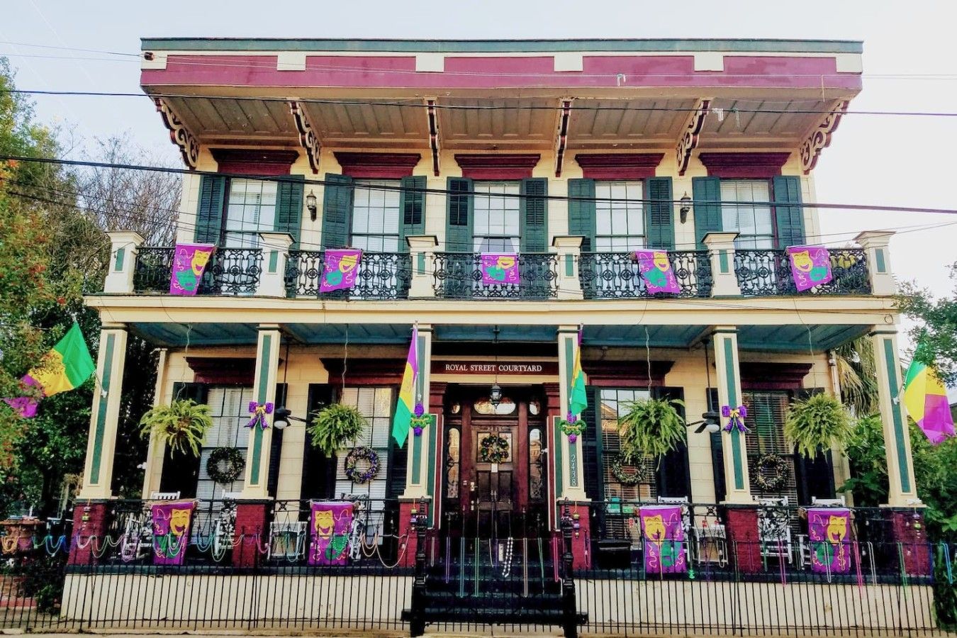 A two-story building with a balcony, a sign reading 'ROYAL STREET COURTYARD,' and multiple flags.