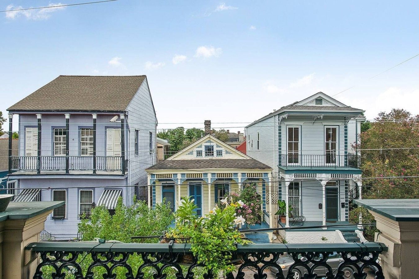 A row of three-story buildings with balconies, a central building with a gabled roof, and a fence in the foreground.