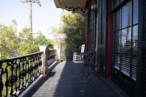 A balcony with a metal railing, a rocking chair, and a table.
