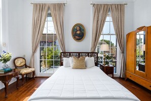 Une chambre d’hôtel avec un grand lit, un tableau au mur et une vue sur l’extérieur.