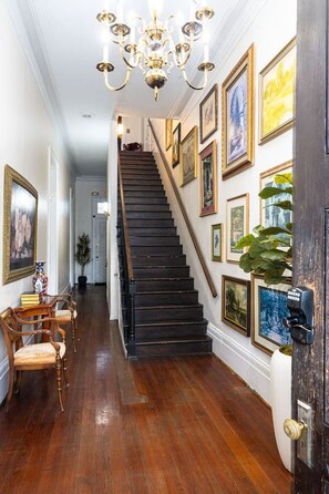 A staircase with a dark wooden finish, flanked by framed artwork on the walls, leading to an upper level.