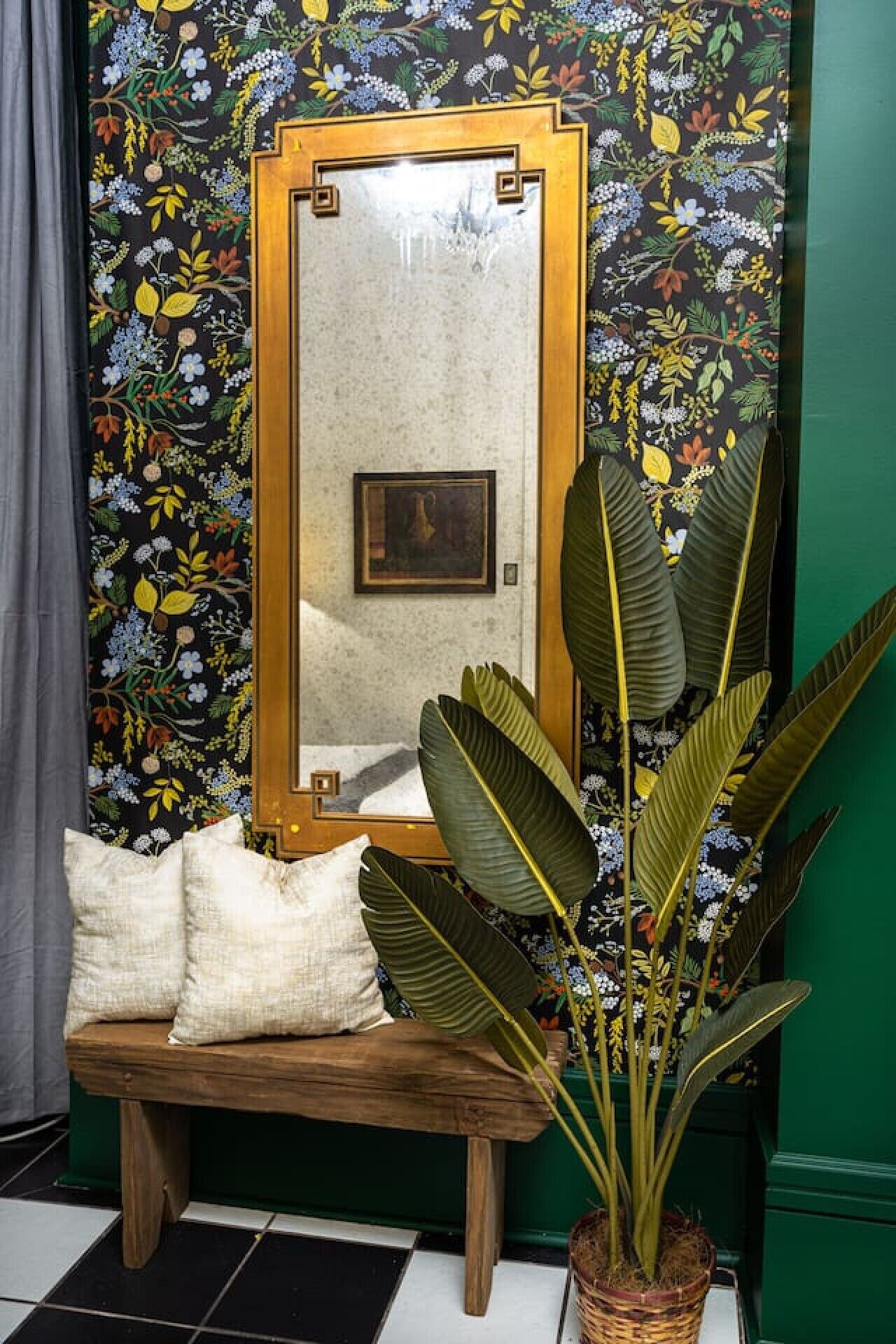 A room with a wooden bench, a large mirror, and a potted plant.