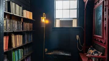 A room with a bookshelf, a window, a lamp, and a mirror.