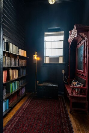 A room with a bookshelf, a window, a lamp, and a mirror.