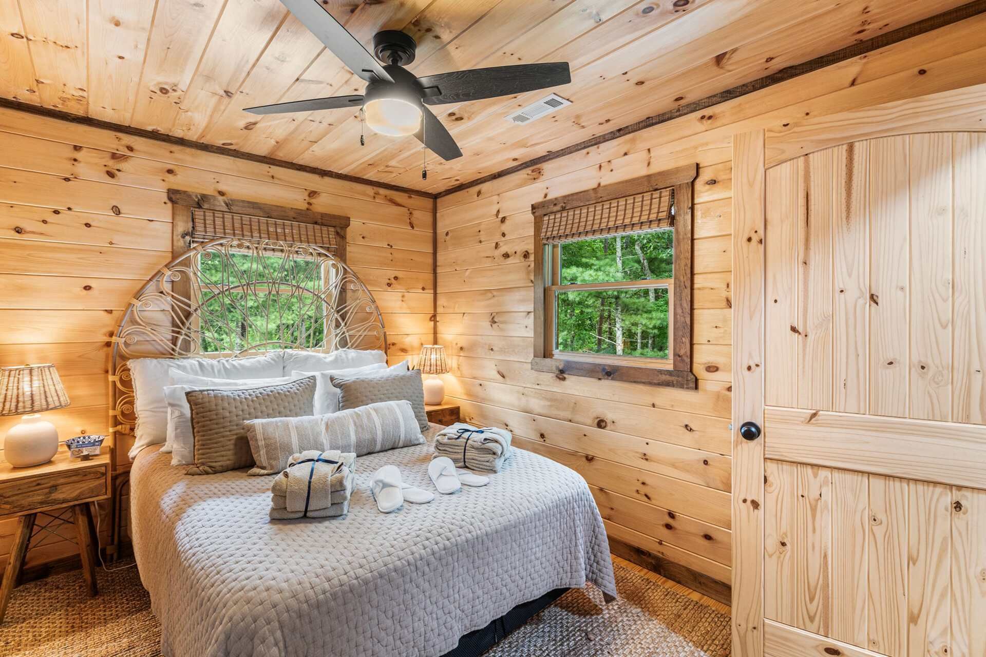 Une chambre à coucher dans une cabane en bois, avec un lit, des oreillers, une table de chevet, une lampe et une fenêtre.