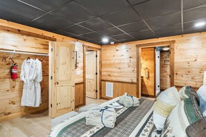 A wooden room with a bed, towels, and a fire extinguisher. - Spa, 2 Fireplaces, Game Rm, Firepit, Quiet Views (Epworth)