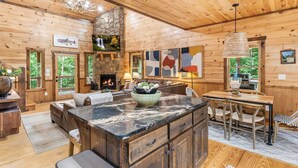A log cabin interior with a fireplace, stone accent wall, wooden furniture, and artwork. - Spa, 2 Fireplaces, Game Rm, Firepit, Quiet Views (Epworth)