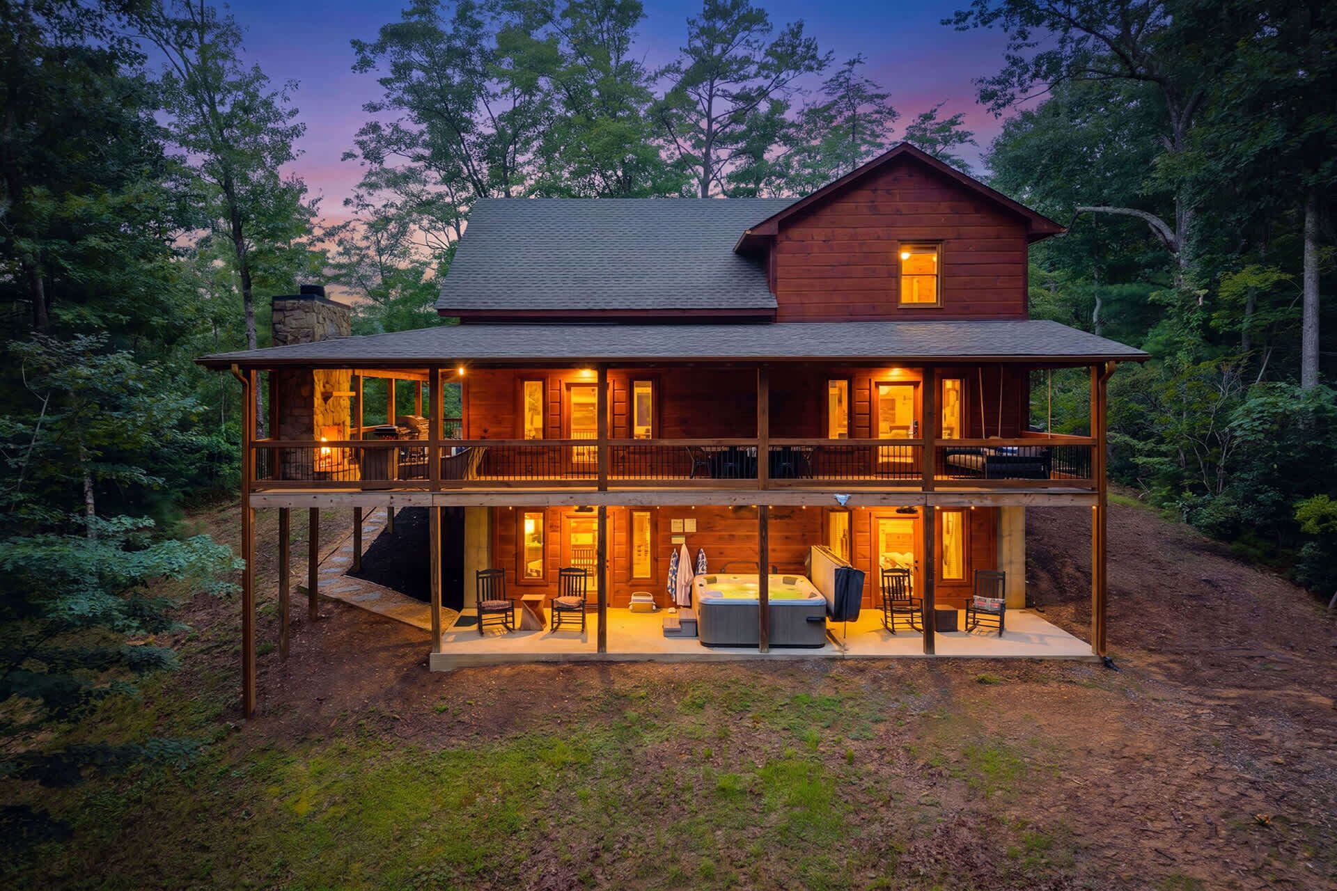 A two-story wooden cabin with a balcony, a hot tub, and a fireplace.