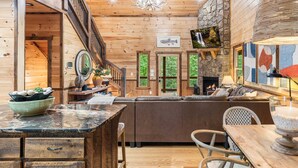 A wooden interior with a fireplace, a stone wall, and a wooden staircase. - Spa, 2 Fireplaces, Game Rm, Firepit, Quiet Views (Epworth)