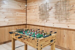 Ein Zimmer mit Holzboden, einem Kicker und einer Wand aus Holz mit geometrischem Muster.