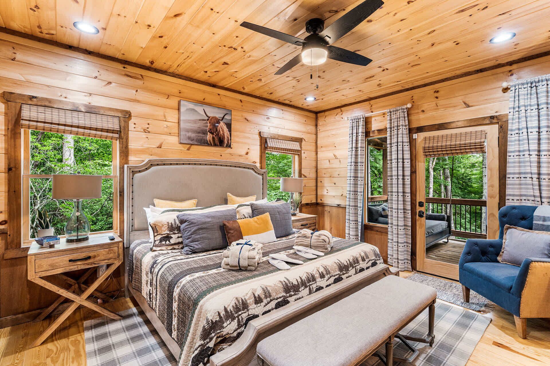 A wooden cabin bedroom with a bed, bedside tables, a bench, and a ceiling fan.
