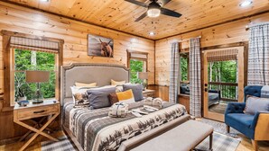 A wooden cabin bedroom with a bed, bedside tables, a bench, and a ceiling fan. - Spa, 2 Fireplaces, Game Rm, Firepit, Quiet Views (Epworth)