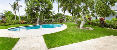 A swimming pool surrounded by a well-maintained lawn and various trees.
