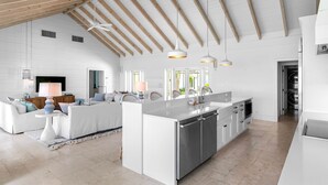 Un'ampia cucina con isola centrale, mobili bianchi e illuminazione a sospensione.