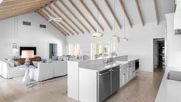 Una cocina amplia con una isla central, armarios blancos e iluminación colgante.