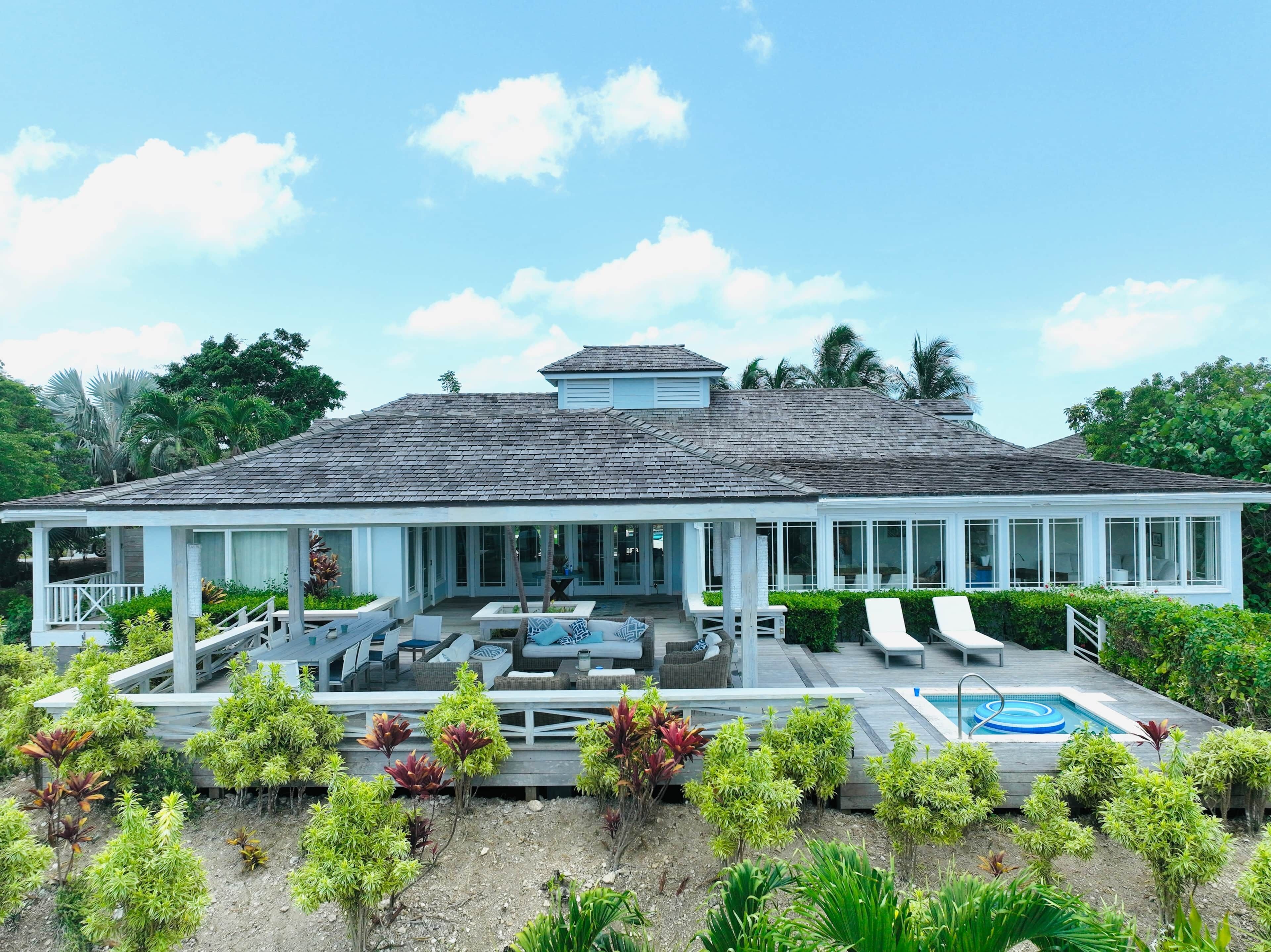 A large house with a covered patio area, outdoor seating, and a swimming pool.