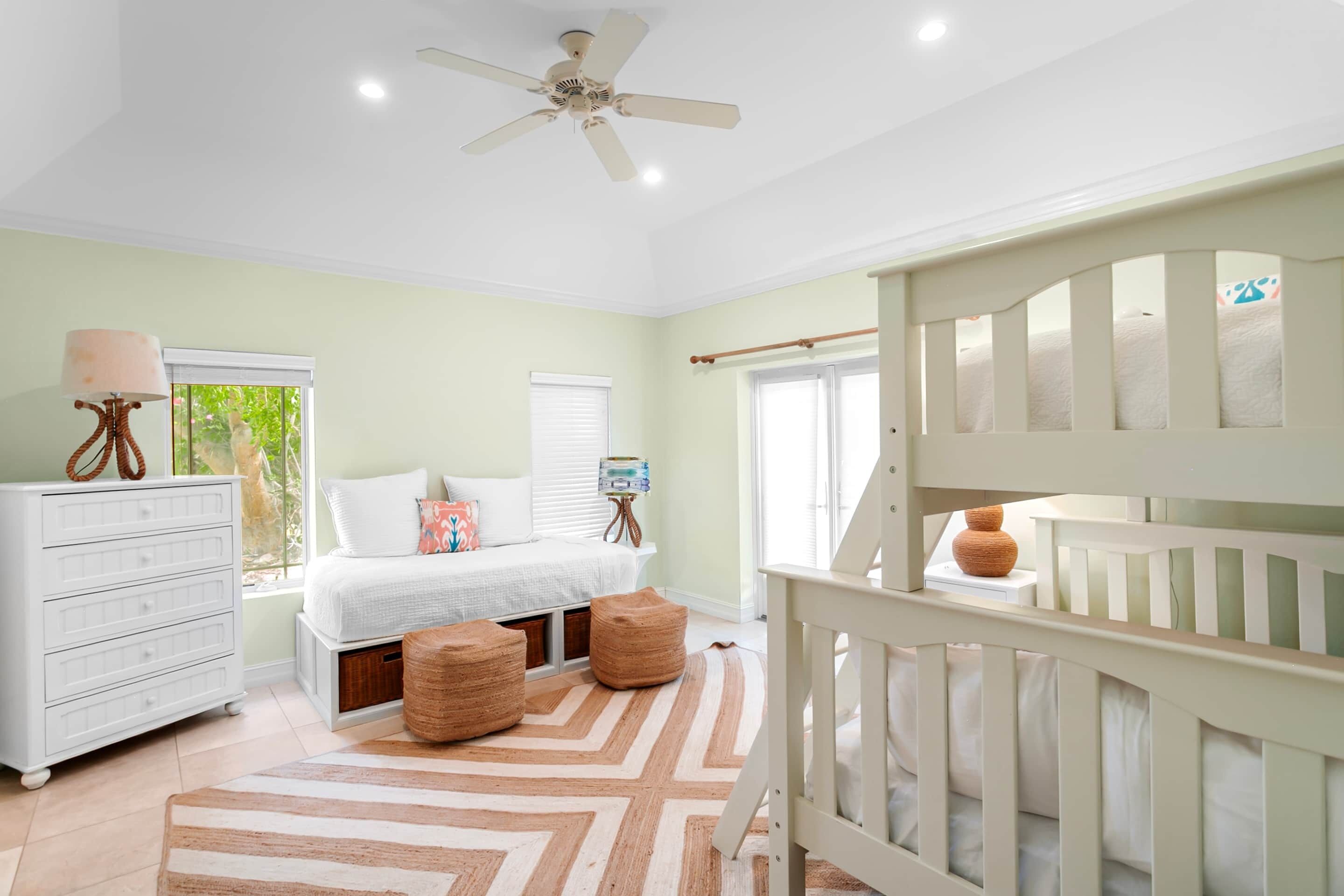 A bedroom with a bed, dresser, and a crib.
