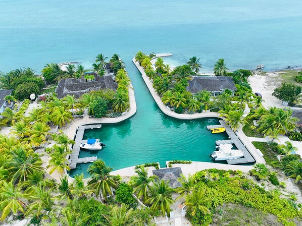 Ein Resort mit einem zentral gelegenen Schwimmbad, umgeben von Palmen und einem Strand.
