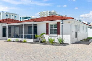 A single-story building with a red-tiled roof, white walls, and a small garden area with various plants. - A10 - Gulf Breeze Getaway (Siesta Key)