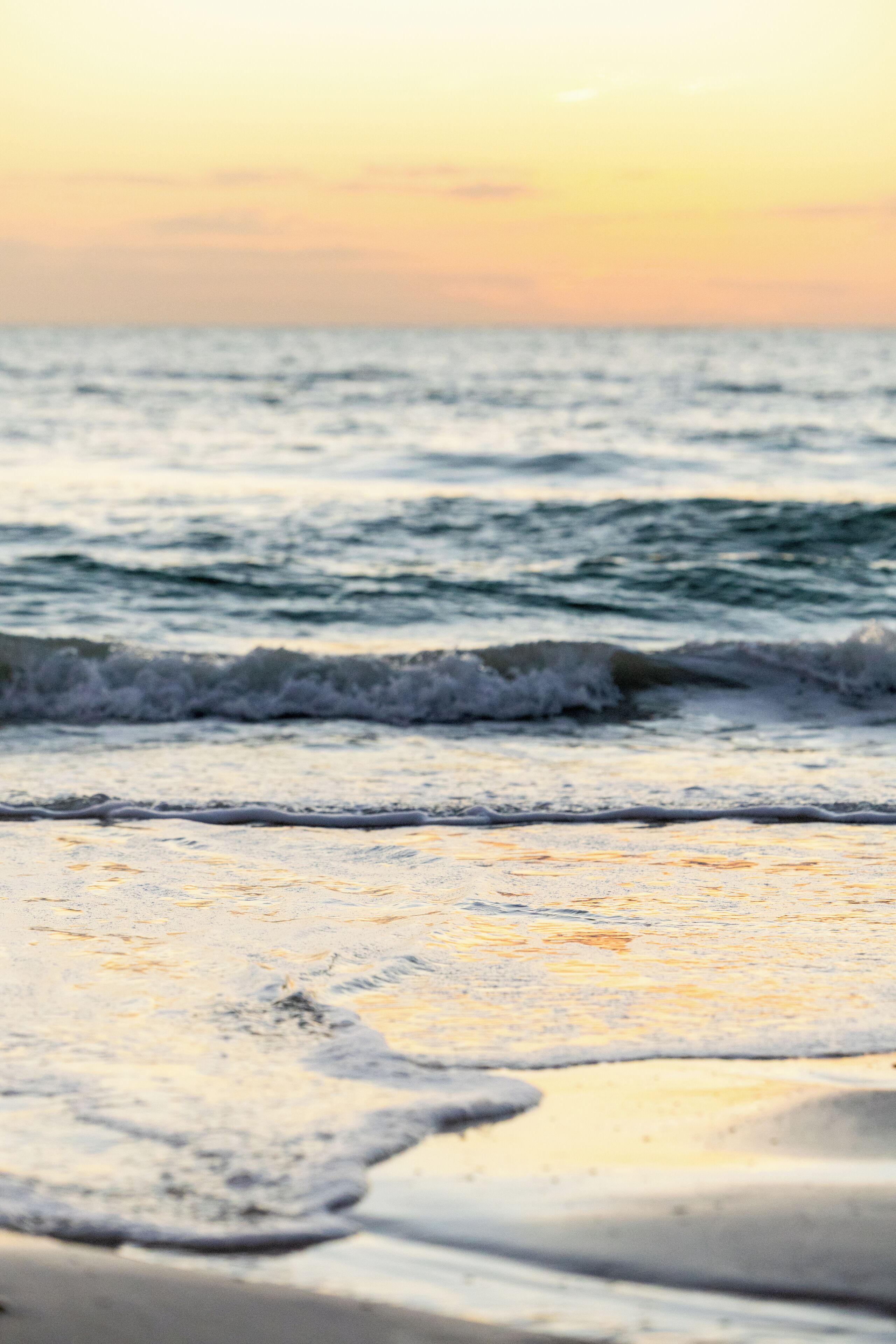 Uma praia com ondas e um pôr do sol.