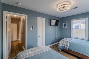 A bedroom with two beds, a television, a ceiling light fixture, and a window with blinds. - 1-story 3BR Near Medical Center & Downtown Houston (Houston)