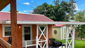 A house with a covered patio, a door, and a small outdoor seating area.