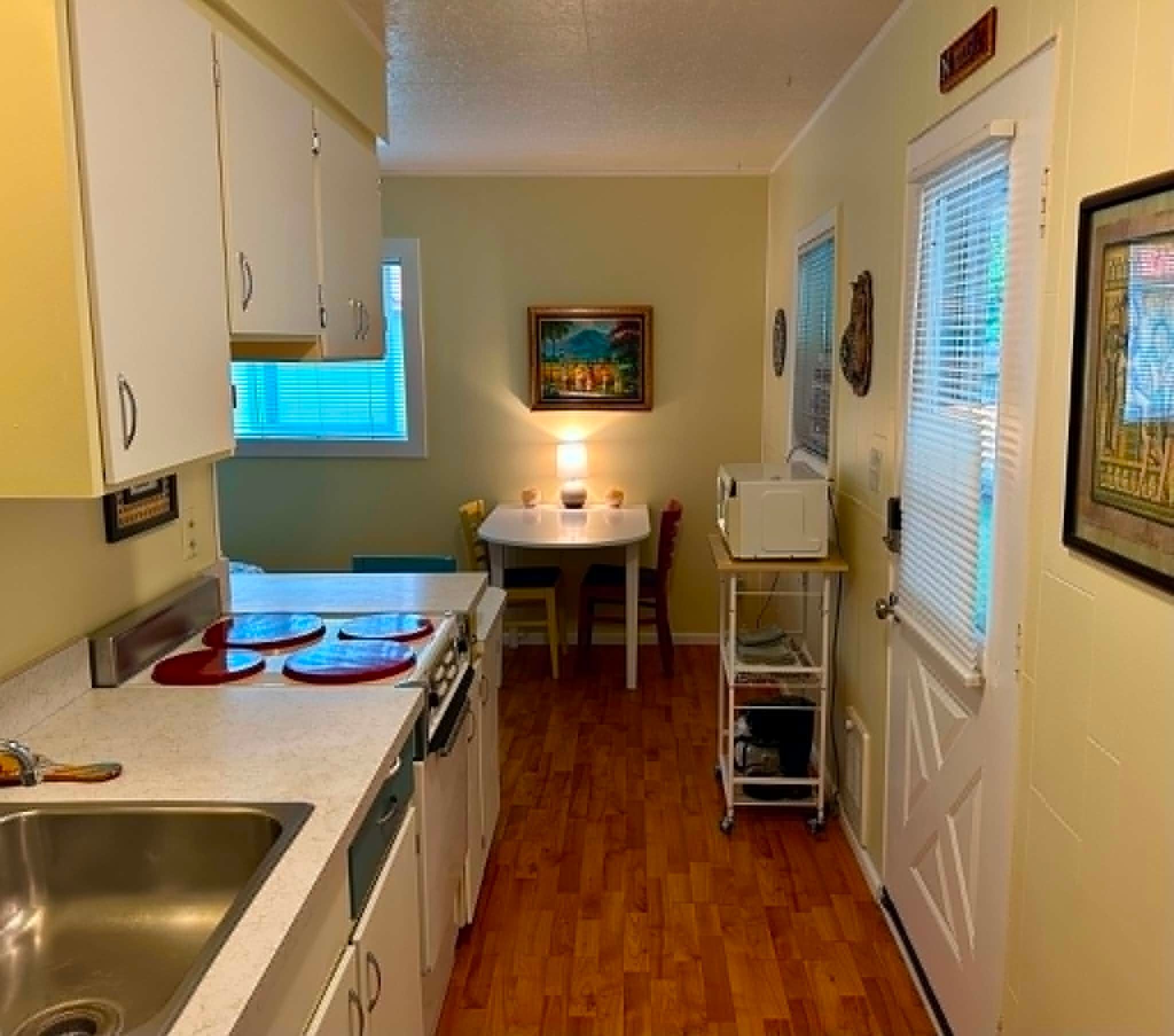 A compact kitchen with a sink, stove, and a dining area with a table and chairs.