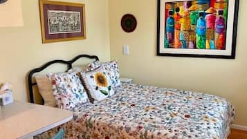Une chambre à coucher comprenant un lit, une chaise, une table et deux œuvres d’art encadrées accrochées au mur.