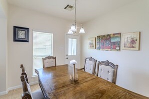 Una sala da pranzo con un tavolo in legno, quattro sedie imbottite, un lampadario e decorazioni alle pareti.