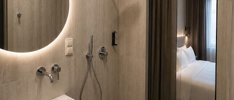Een moderne badkamer met een ingebouwd wastafelmeubel, een douche en een grote spiegel.