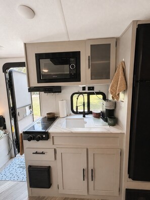 Una kitchenette compacta con microondas, estufa, pileta y alacenas.