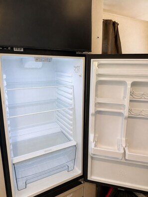 An open refrigerator with multiple shelves and a freezer compartment. - Lake Weiss Retreat Private Fenced RV Lot (Centre)