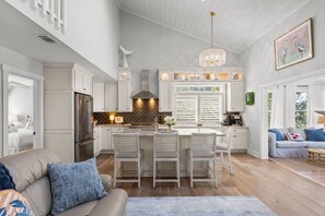 Una cocina moderna con armarios blancos, una isla central y un comedor.