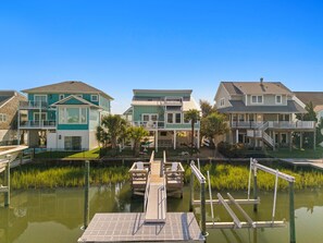 A waterfront property with a dock, a pool, and houses with balconies. - Na Da Shell OIB- Canal Home, Private Pool! (Ocean Isle Beach)