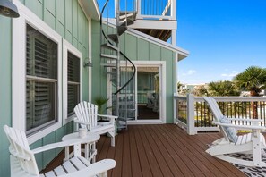 A wooden deck with outdoor seating, a spiral staircase, and a view of the surrounding area. - Na Da Shell OIB- Canal Home, Private Pool! (Ocean Isle Beach)