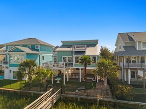 A row of beachfront houses with balconies, a pool, and a fenced yard. - Na Da Shell OIB- Canal Home, Private Pool! (Ocean Isle Beach)
