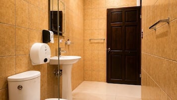 Un baño con inodoro, lavamanos y una puerta de madera oscura.